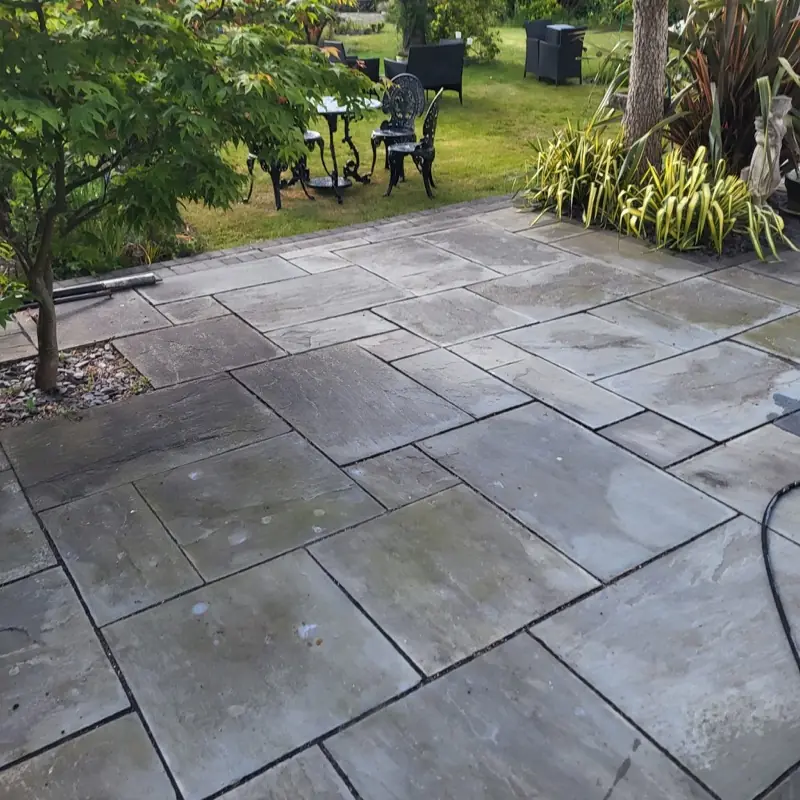 Grey sandstone patio dulled with algae before cleaning